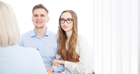 Young couple, eager to sign a bank loan agreement, meets with their broker agent. - 787144907