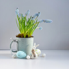 Easter composition with white rabbit, eggs and light blue muscari flowers in cup. Easter still life