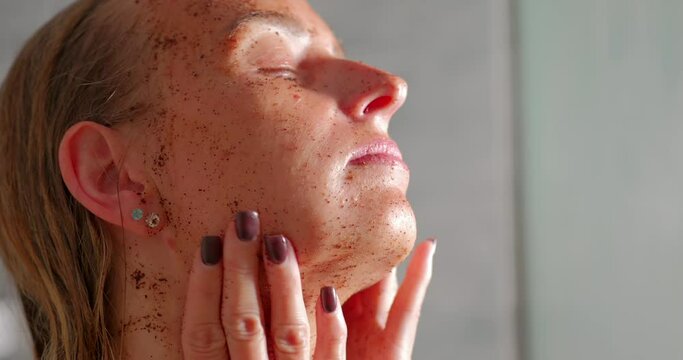 A young woman massages her face with a scrub