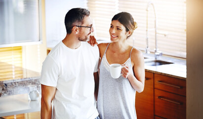 Love, coffee and couple hug in a kitchen for morning, conversation and bonding at home together....
