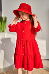 A little girl in a dress and matching hat, posing in the sun and smiling brightly