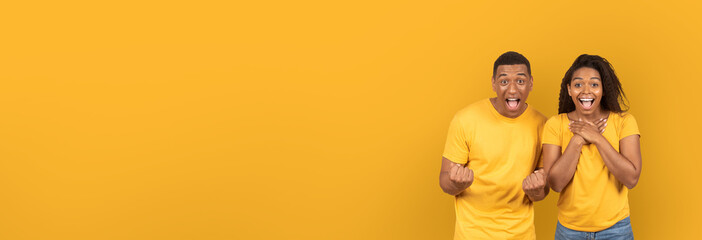 Excited african american couple against yellow background