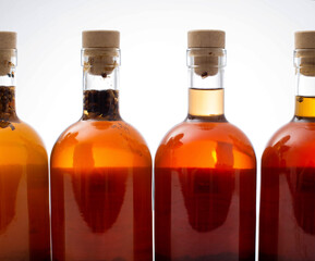 Bottles with transparent brown alcoholic drink on a white background. Homemade herbal tincture of...