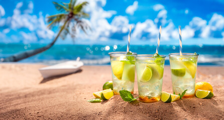 Tasty and fresh lemonade with ice on sandy beach.