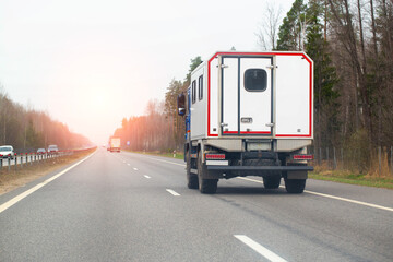 A special cargo vehicle with the body of a mobile repair workshop is driving along a country road against the backdrop of sunset in the spring. Copy space for text, industry