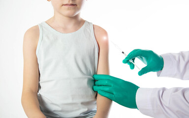 Doctor's hands in green medical gloves vaccinate a child girl in the shoulder against the flu, copy space for text. Revaccination - 787161536