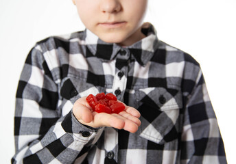 The girl holds red chewable vitamins in the form of bears in her hand. The concept of a multivitamin complex for the health and immunity of children during growth. Vitamin A and B complex, close-up