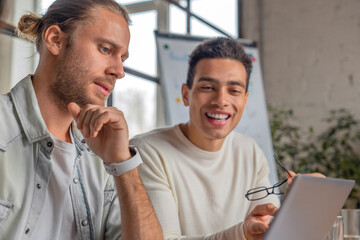Close up shot of two young modern men in smart casual wear working together while sitting in the...