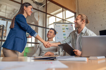 Business people finishing up a meeting. Man shaking hands with female client after successful deal....