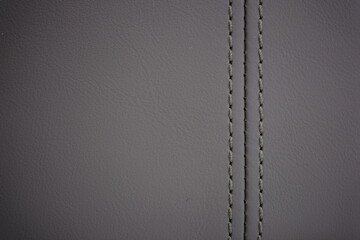 Gray contrast thread on natural gray leather car seat close-up