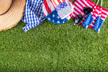 July 4, Independence Day traditional American picnic background. Plates, glasses, USA flags on green lawn or meadow grass, with blanket or tablecloth for picnic, sunglasses, copy space top view - 787167311