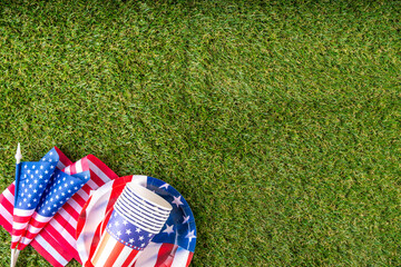 July 4, Independence Day traditional American picnic background. Plates, glasses, USA flags on green lawn or meadow grass, with blanket or tablecloth for picnic, sunglasses, copy space top view - 787167373