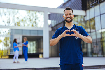 Closeup shot of a medical practitioner making a heart shape with his hands. Cheerful male surgeon...