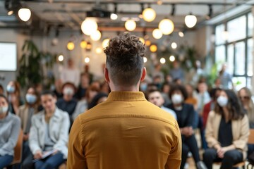 Employees attending corporate business training or seminar. Professional business coach speaking for multiethnic people in modern spacious office interior. Diverse audience, back view from behind