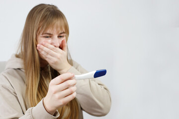 woman in shock with pregnancy test. woman with pregnancy test not happy