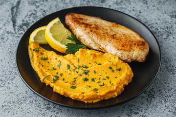 delicious mashed sweet potatoes and fried chicken breast on a light stone background