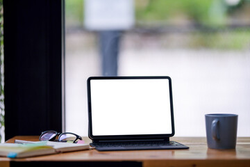 Open digital tablet with blank screen. Financial charts, hot coffee, and office supplies are on the table.