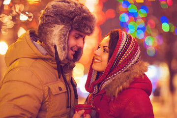 Happy couple in love outdoor in evening Christmas lights
