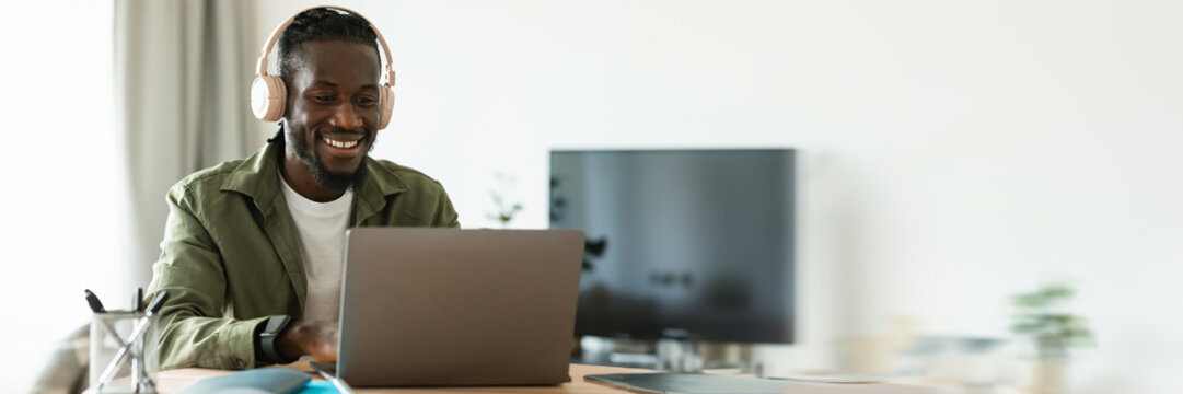 Happy african american man in headset working on laptop computer