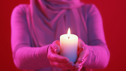 Praying fire. Islamic holiday. Candle light. Unrecognizable woman in hijab holding burning wax...