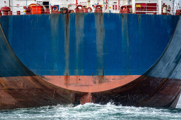 Big blue container ships stern with the rudder pushes a giant wave through the ocean.