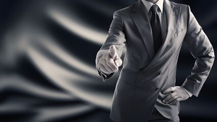 A close-up of a man's torso and arm, dressed in a formal suit. He is pointing his index finger forward, suggesting direction or emphasis on something in front of him