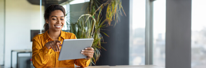 Happy black businesswoman using modern tablet, working online in office