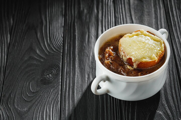 delicious original french onion soup on a black rustic wooden background