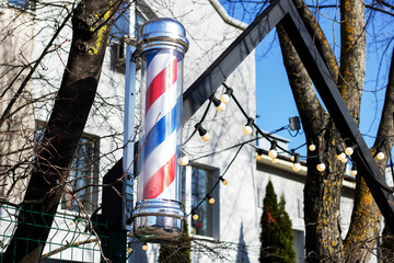 A patriotic barber pole decorates the cityscape, hanging under the blue sky