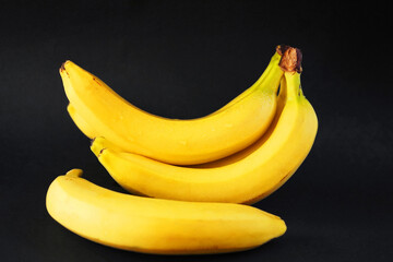 Several ripe yellow bananas on a dark background