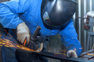 Locksmith wearing special goggles works with angle grinder sparks in metalworking