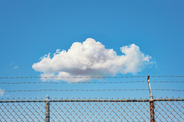 A cloud above a chained fence