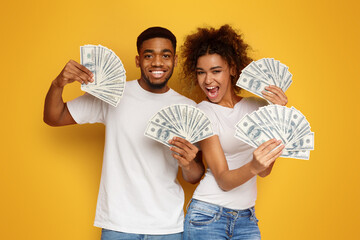 Satisfied couple holding bunch of money banknotes