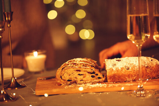 Woman cutting freshly baked homemade pie with knife, celebrating Christmas Eve with friends at home.