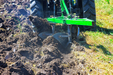 Fototapeta premium In spring, tractor plows are used to cultivate soil and prepare field for sowing grain