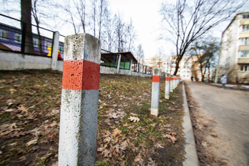 Row of red and white striped concrete poles on asphalt road