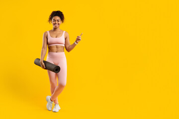 Smiling woman with yoga mat on yellow
