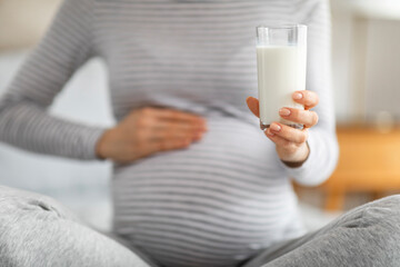 Close-up of pregnant woman's belly and glass of milk
