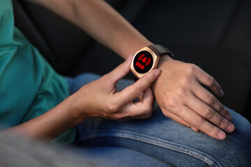 Woman using SOS function on smartwatch in car, closeup
