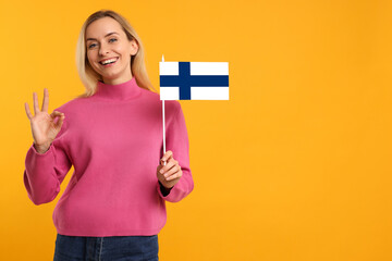 Happy young woman with flag of Greece showing OK gesture on yellow background