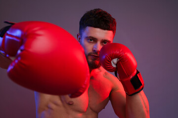 Man in boxing gloves fighting on color background