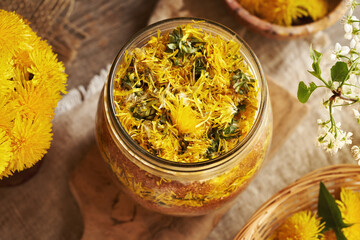 Preparation of homemade raw dandelion syrup from fresh flowers and cane sugar in a glass jar