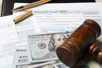 Tax return forms, dollar banknotes, gavel and pen on table, closeup
