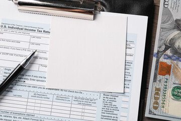 Tax return form, paper note, dollar banknotes and pen on table, top view