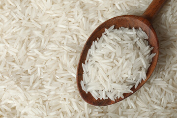 Raw basmati rice and spoon as background, top view. Space for text