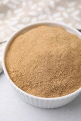 Dietary fiber. Psyllium husk powder in bowl on light grey table, closeup