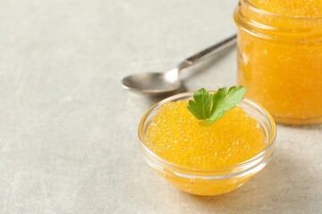 Fresh pike caviar in bowl, parsley and spoon on light grey table, closeup