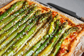 Open pie with asparagus and cheese on gray background