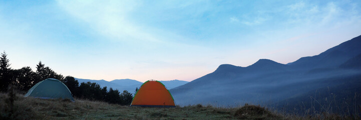 Camping tents on mountain slope in morning, banner design