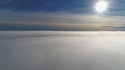 Sun through fog. Antarctica aerial drone view flight. White bright polar sun disk appears in the...